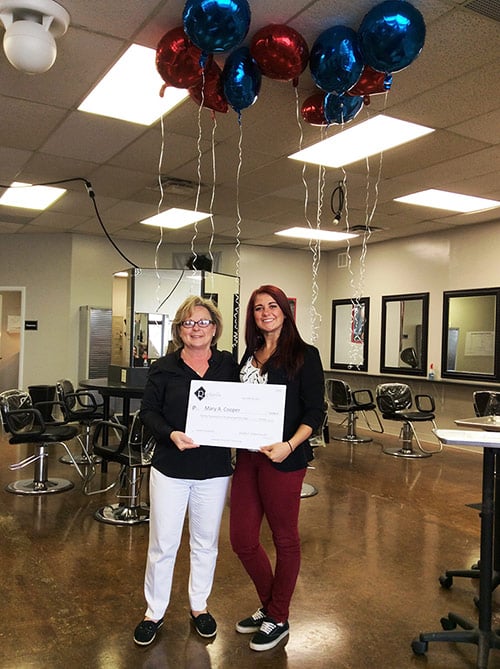 Our 2015 summer scholarship winner is Mary Cooper. In this picture she is being presented with the scholarship certificate and there are red and blue helium-filled balloons floating at the ceiling with ribbons hanging down.