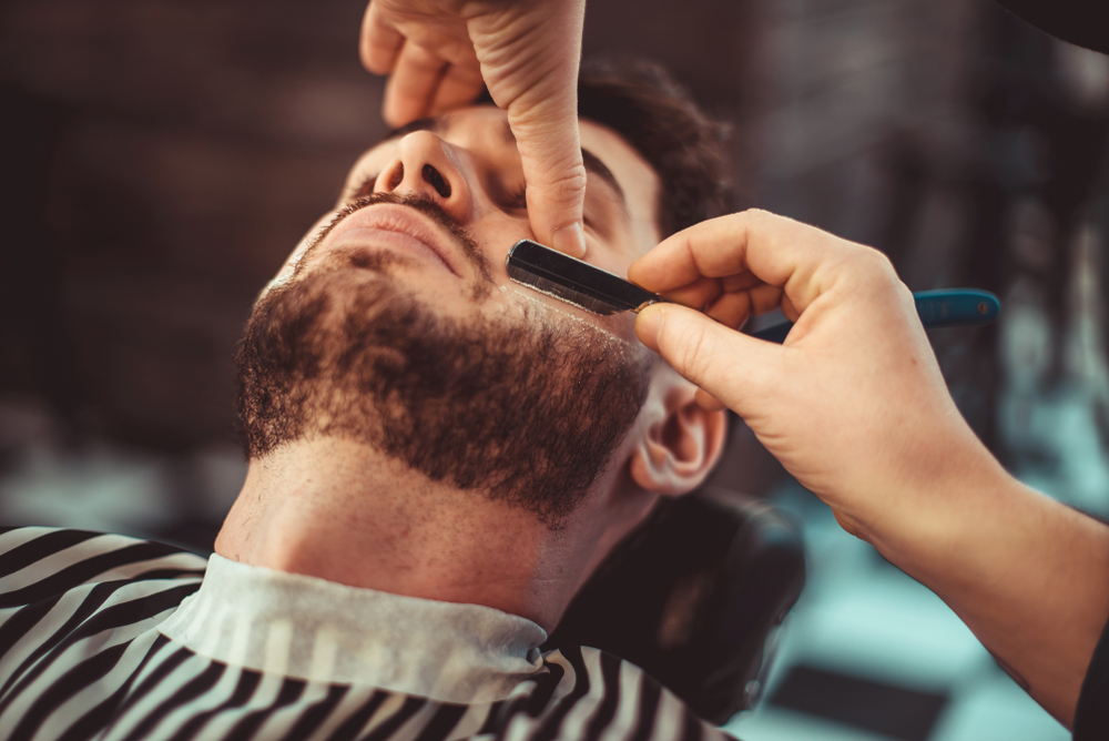 barber shaving a man's beard
