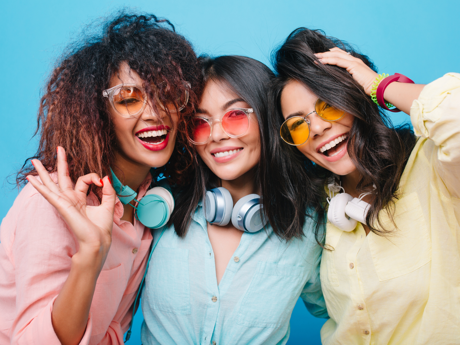 three women laughing and smiling in pastel shirts