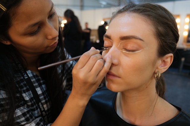A makeup artist puts make up on a woman's face