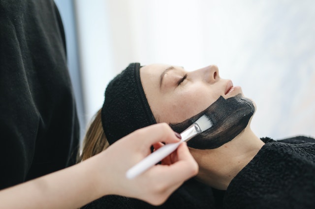 Esthetician applies charcoal mask to client