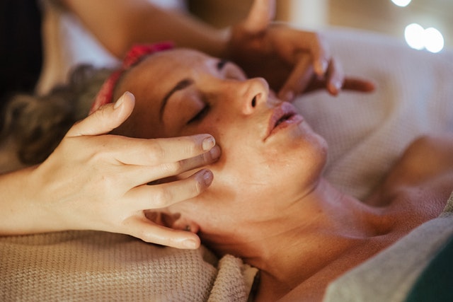 Massage therapist massaging the face of their client